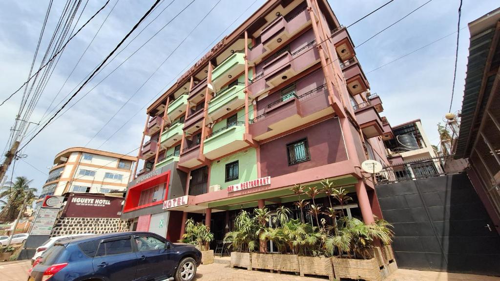 un edificio con un'auto parcheggiata di fronte di Ngueye Hotel a Yaoundé
