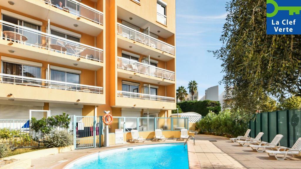 a hotel with a swimming pool in front of a building at Résidence Pierre & Vacances La Rostagne in Juan-les-Pins