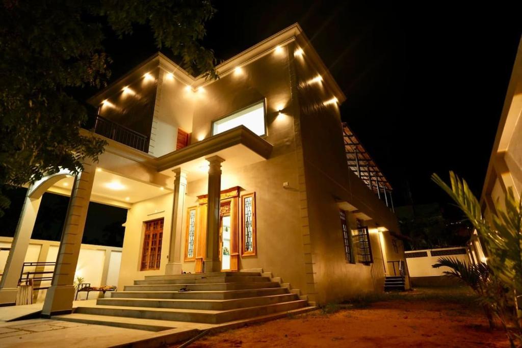 a white house with stairs and lights at night at Desert Beach House with swimming pool in Kuilapayam