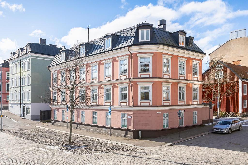 a large pink building with a black roof on a street at Trossö Vandrarhem in Karlskrona