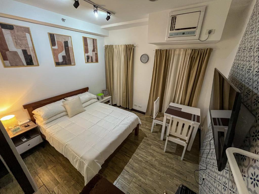 a bedroom with a bed and a table and a chair at Woodland Tagaytay in Tagaytay