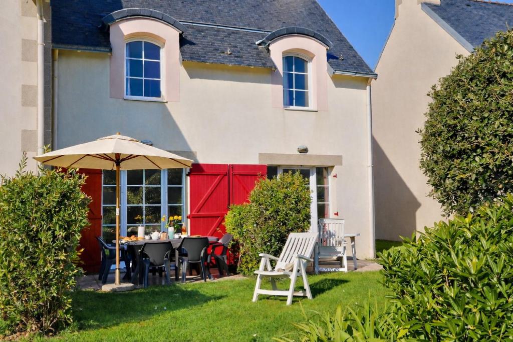 a house with a table and chairs in the yard at LocaLise - Maison E4 au Guilvinec - A 20m de la mer avec jardin et piscine - Tout à pied, plages, port, centre, commerces, marché - Wifi inclus - Linge de lit inclus - Animaux bienvenus in Le Guilvinec
