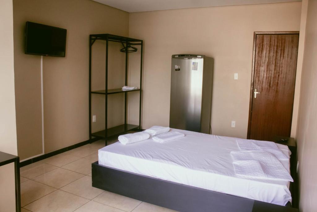 a bedroom with a bed with white sheets and a television at Kitnet em Betim no centro in Betim