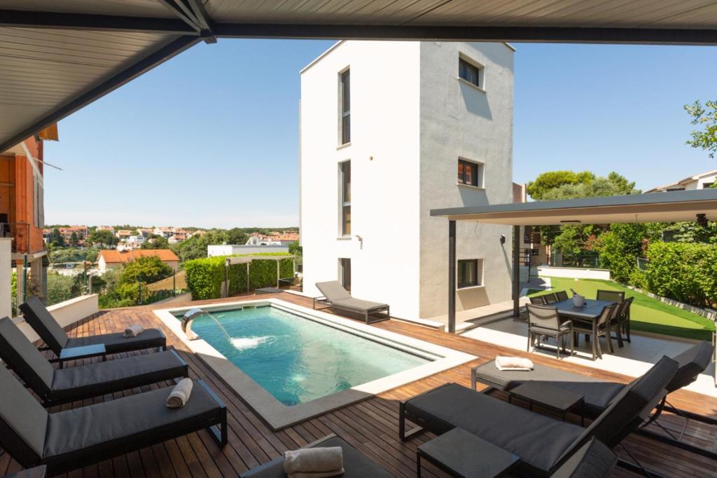an outdoor patio with a swimming pool and a deck with furniture at Villa Bellavista in Medulin