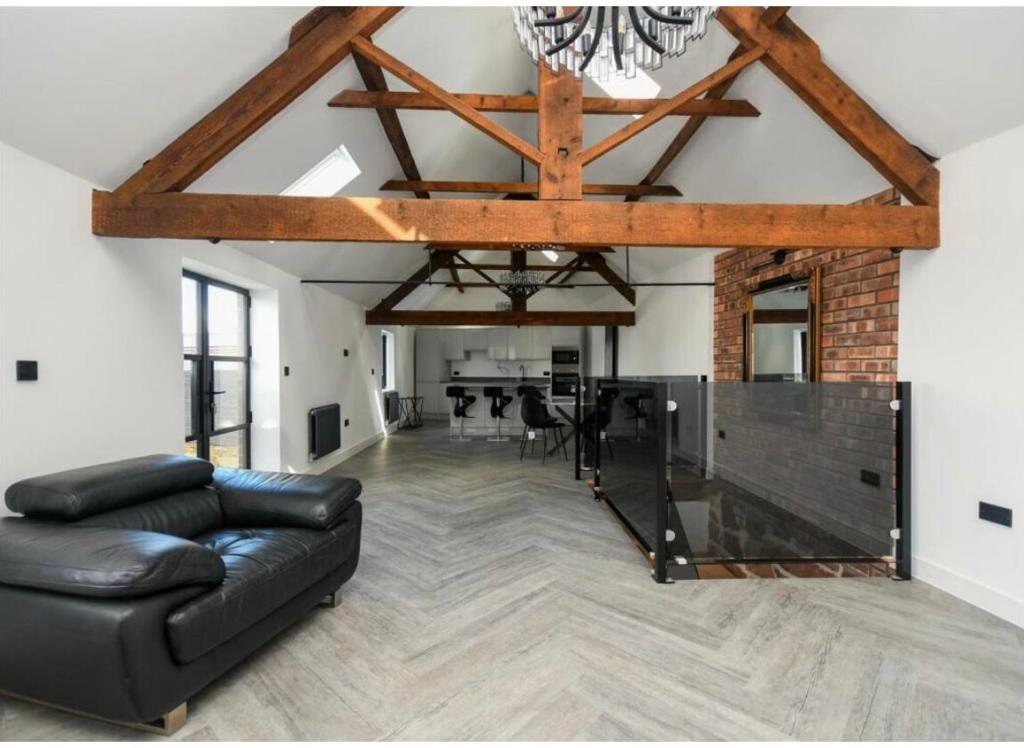 a living room with a black leather couch and a table at Sandstone Grange in Albrighton
