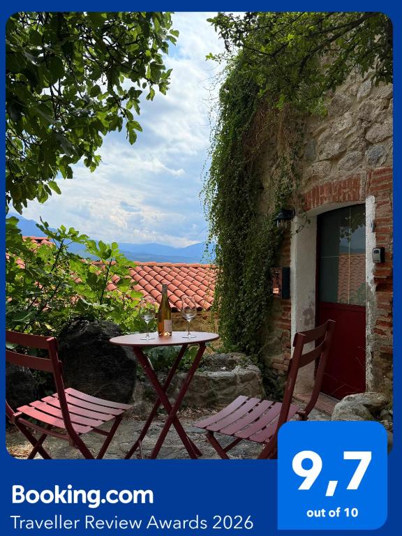 a table and two chairs sitting next to a building at Charming stone house in Eus - Vue sur les Montagnes & Confort 2025 in Eus
