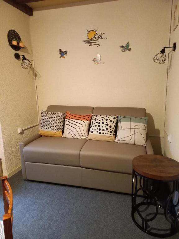 a living room with a couch with pillows and a table at Appartement calme in Eaux-Bonnes