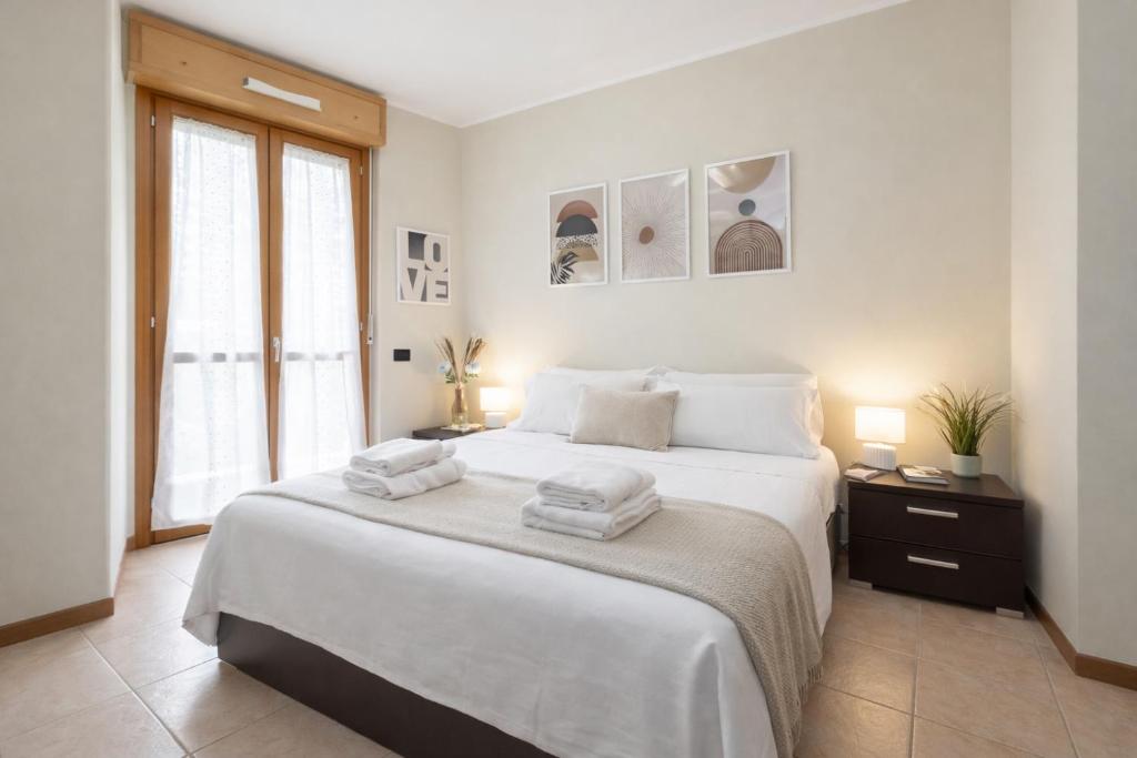 a white bedroom with a large bed with towels on it at Spazio Breda - Free Parking, Private Garage, Metro M1, Balcony, 4 Guests in Milan
