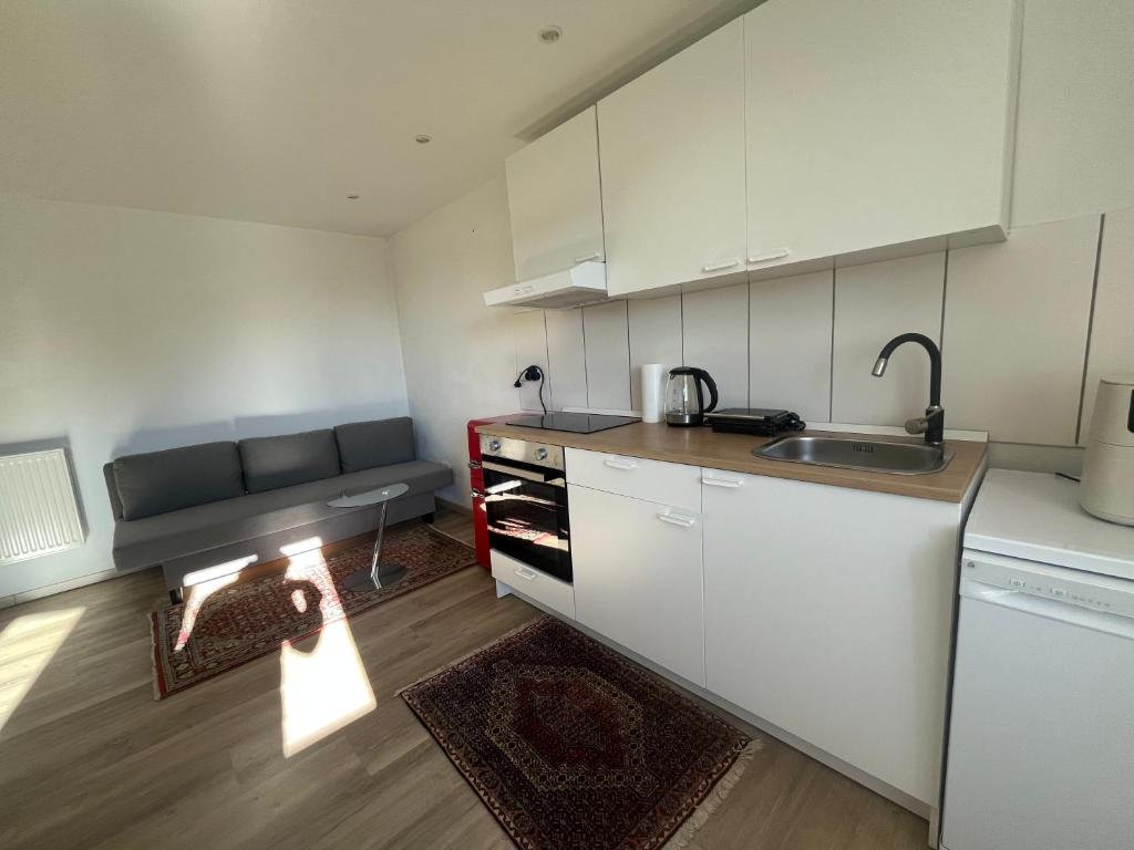 a kitchen with white cabinets and a sink and a couch at Waldsee in Hilgert