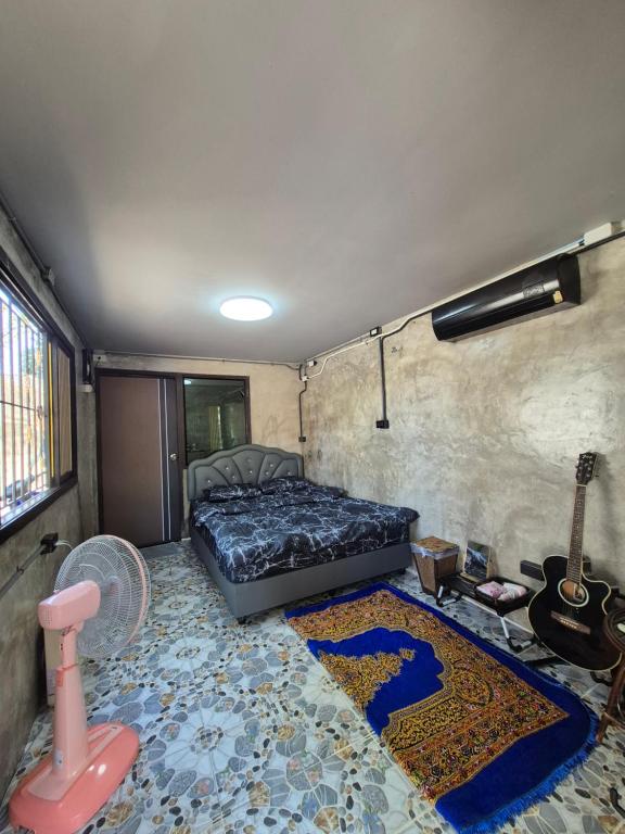 a bedroom with a bed and a guitar and a rug at บ้านพักหลังวัดโลกโมฬี in Chiang Mai