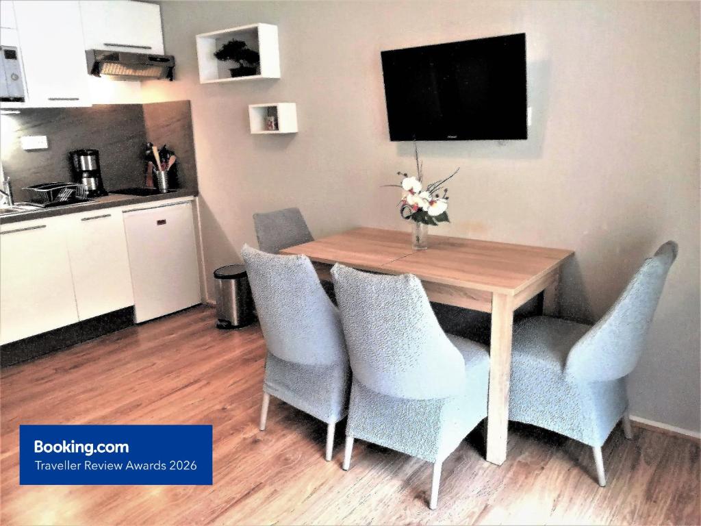a dining room table with blue chairs and a television at Charmant T2, hypercentre, calme, terrasse, parking in Luchon