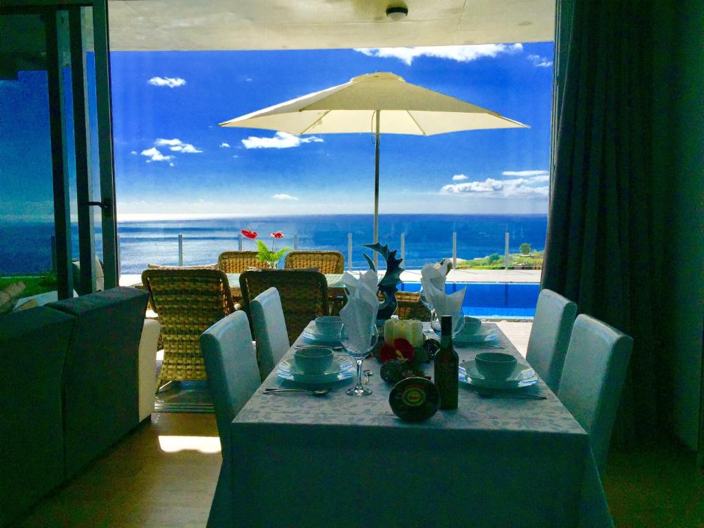 a dining room table with a view of the ocean at Villa Pinheira III heated pool in Calheta