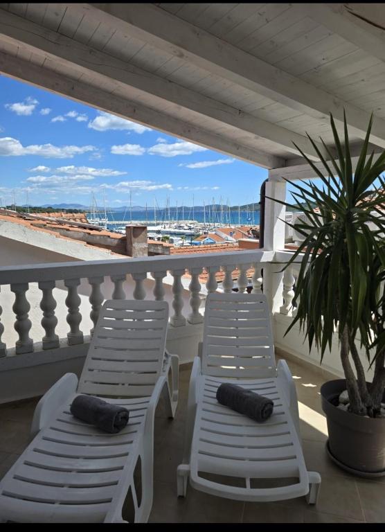 two white lounge chairs on a balcony with a palm tree at House Vodice in Vodice
