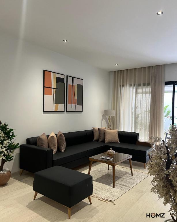a living room with a black couch and a table at Homz Maison in Sukrah
