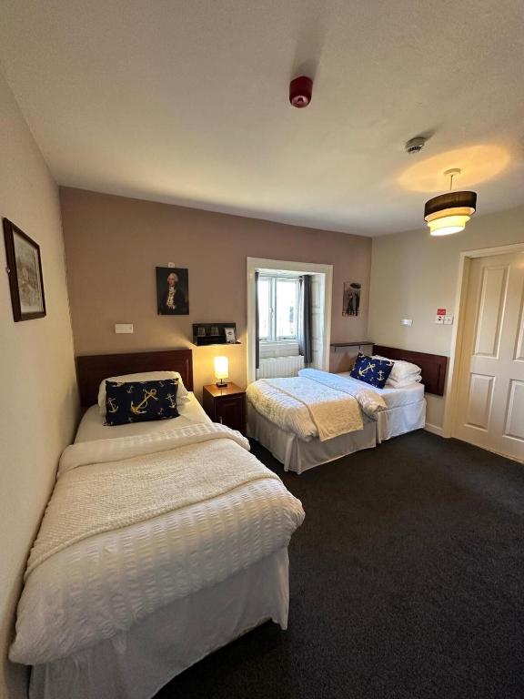 ein Hotelzimmer mit zwei Betten und einem Fenster in der Unterkunft Anchor Hotel in Hexham