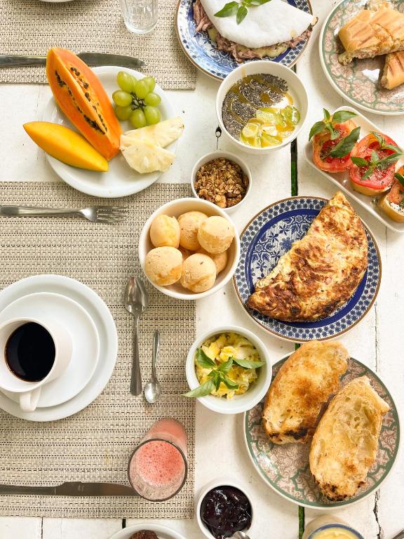 a table topped with plates of food and fruit at Pousada Jardim da Praça in Caraíva