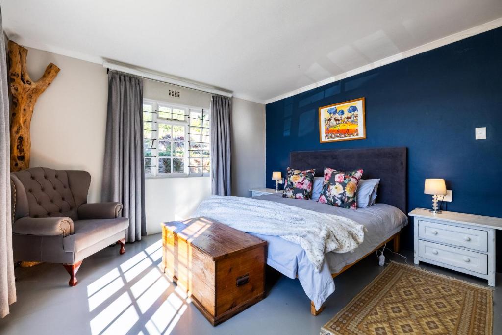 a bedroom with blue walls and a bed and a chair at Dorpsig Cottage in Paarl