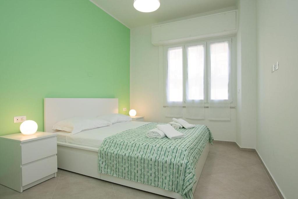 a white bedroom with a bed and a window at Finalpia suite con box auto e deposito bici in Finale Ligure