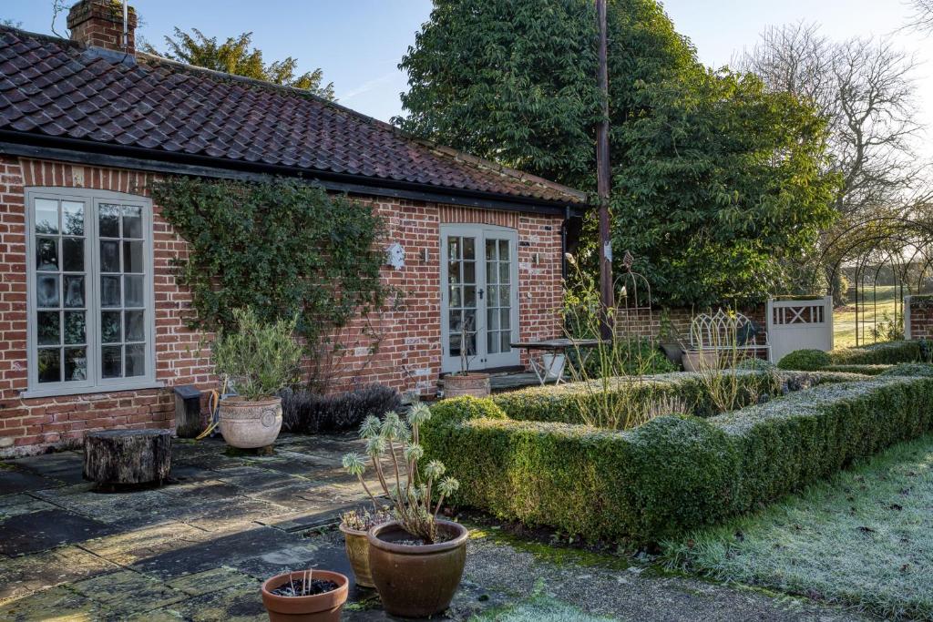 a garden in front of a brick house with plants at The Cottage in Steeple Bumpstead
