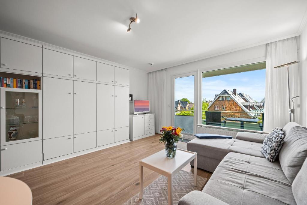 a living room with a couch and a large window at Norderhoog-Whg-33-1-OG-O-Wohnung-33 in Westerland