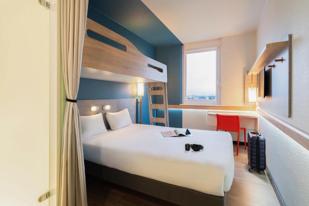 a hotel room with a large white bed and a window at ibis budget Genève Aéroport in Geneva
