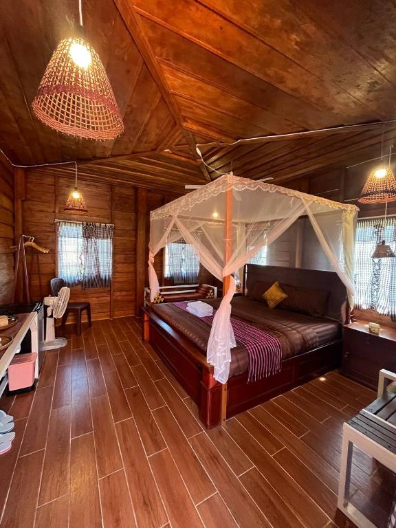 a bedroom with a bed with a mosquito net at Phum Khnhom Bungalow in Battambang