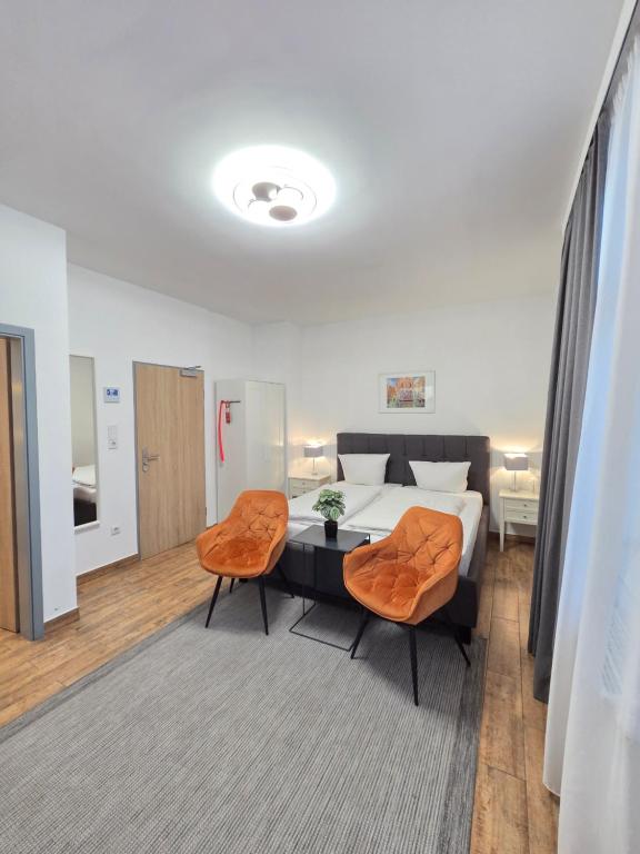 a bedroom with a bed and two orange chairs at Marcel Apartments Leipzig in Leipzig