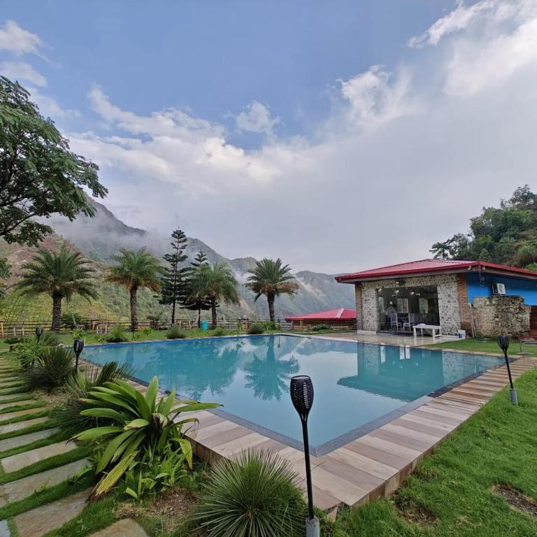 a large swimming pool in front of a house at Fun N Forest Resort in Dehradun