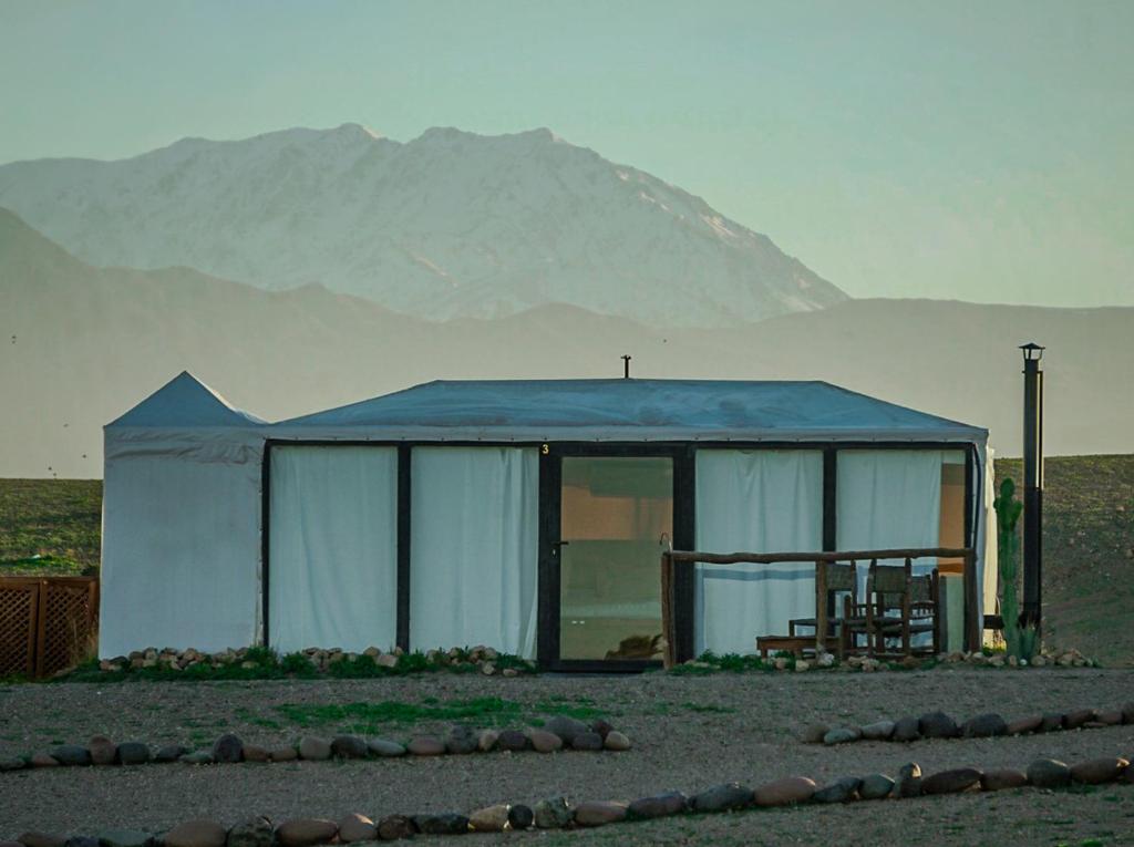 a tent in the middle of a field with a mountain at Emeraude Camp Agafay in El Karia