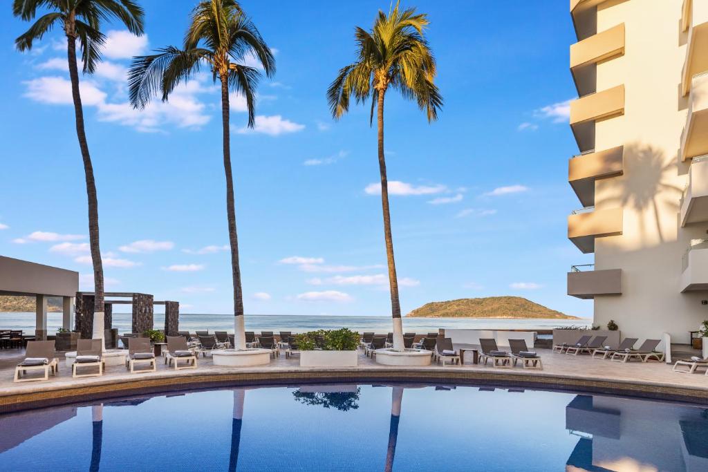 una piscina con palmeras y el océano en Sunvivia by Fiesta Americana Mazatlán, en Mazatlán