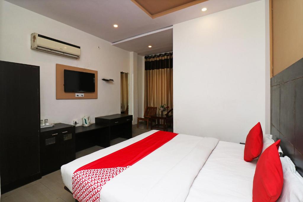 a bedroom with a large white bed with red pillows at Super Hotel O by OYO Surya Continental in Lucknow