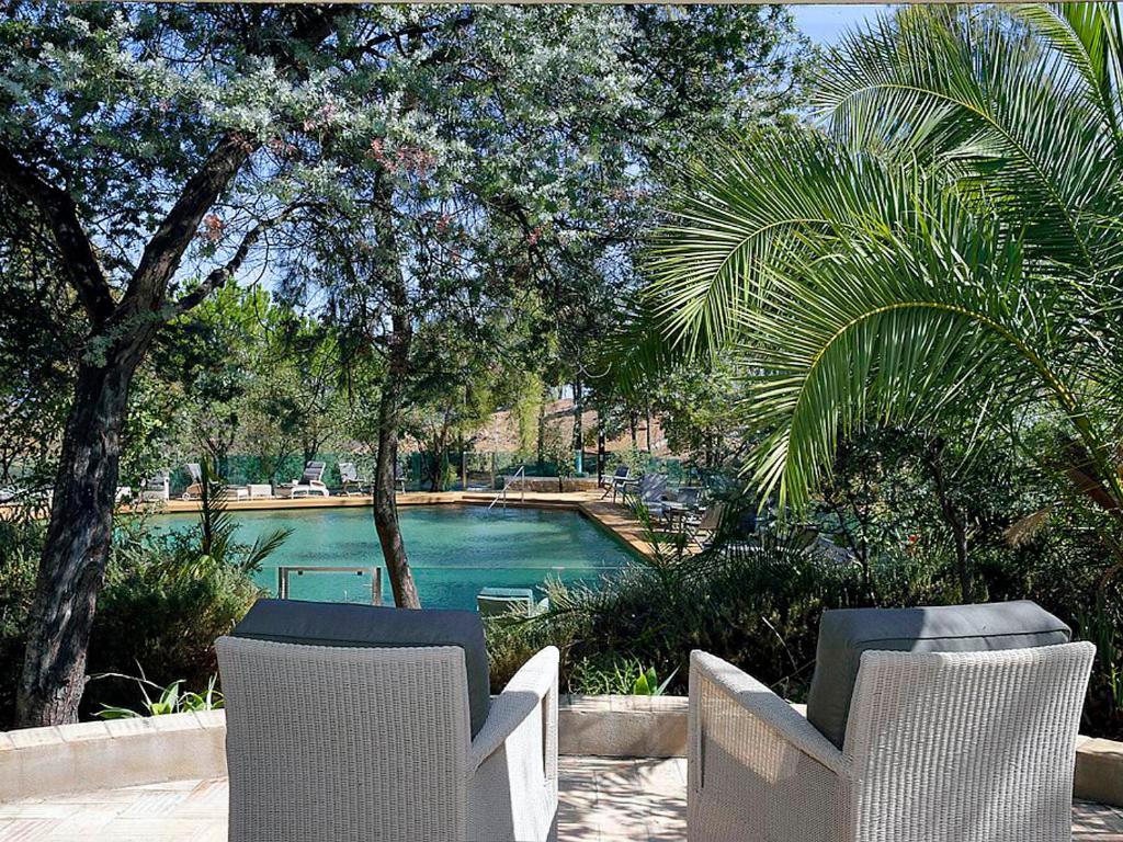 a swimming pool with two chairs and trees at Quinta das Eirinhas-Jardim de Bonsai in Tavira