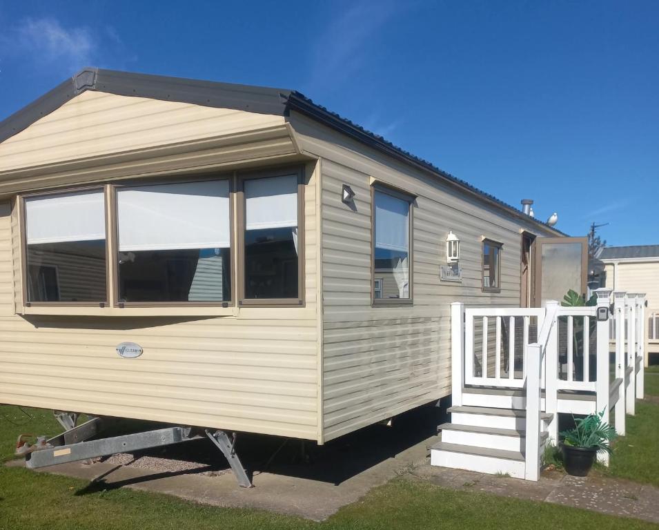 a tiny house with a porch and a staircase at K&J's Caravan Rental in Kinmel Bay