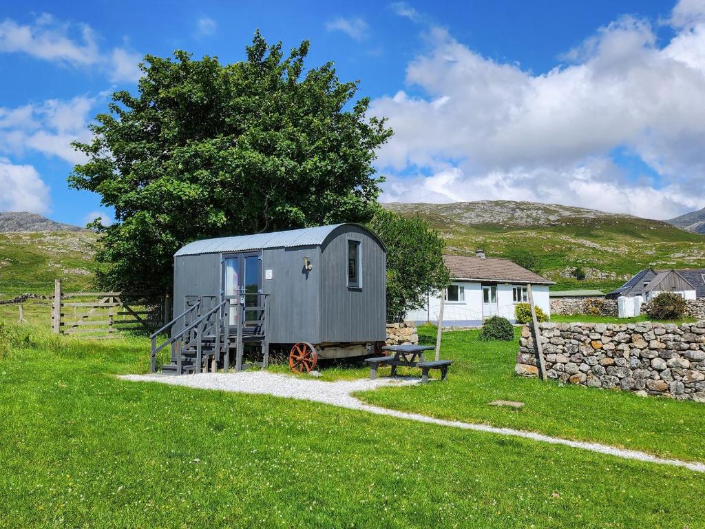 a tiny house in a field with a bench at Shepherds Hut - Uk49096 in Inchnadamph