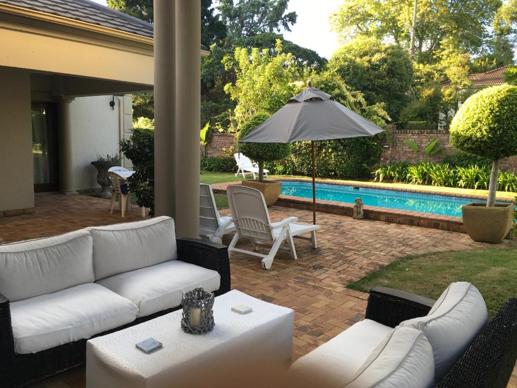 a patio with a white couch and an umbrella at Plovers Rest in George