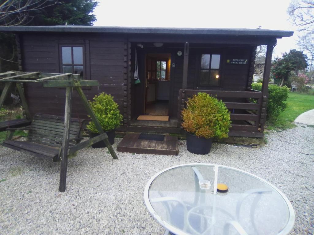 a small cabin with a glass table in front of it at Trevenna Cabin in St Austell
