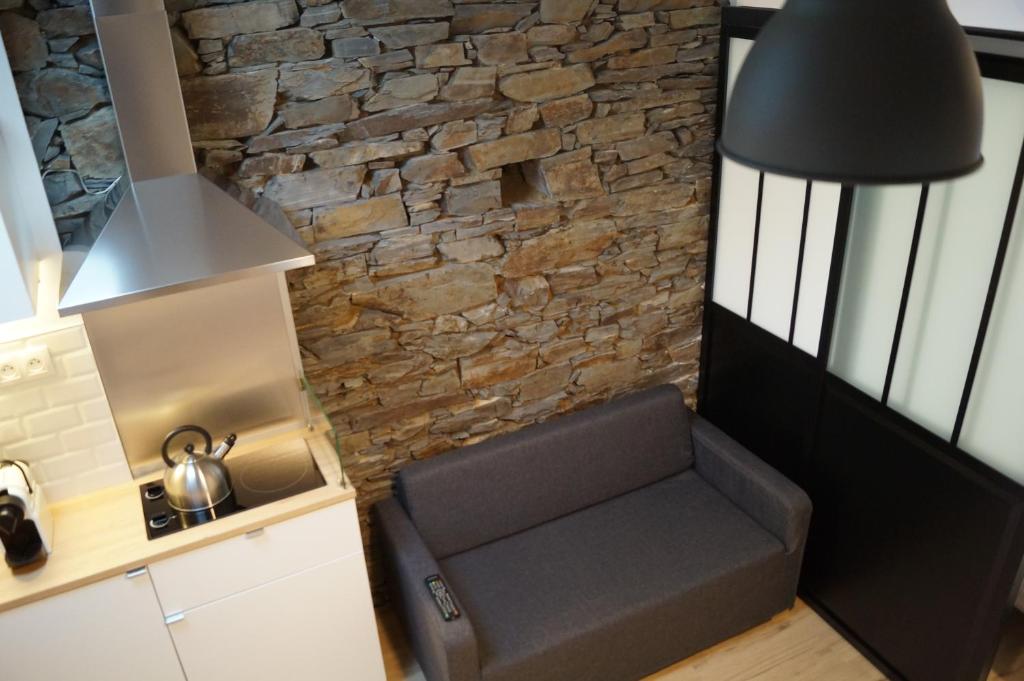 a room with a couch in front of a stone wall at L'atelier in Cancale