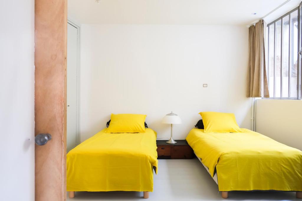 two beds in a room with yellow sheets at Malot 34 in Montreuil
