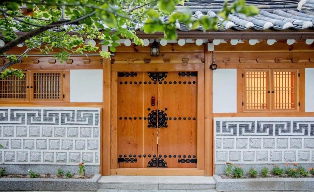 a house with a wooden door and a fence at Moonjarak Dalbit Hanok in Seoul