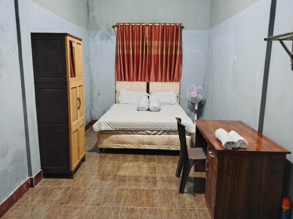 a small bedroom with a bed and a desk at Keluncing Field Homestay in Kotaraja