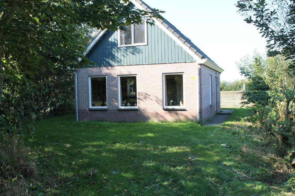 uma casa com duas janelas e um jardim de relva em duin/vuurtorenzicht em De Cocksdorp