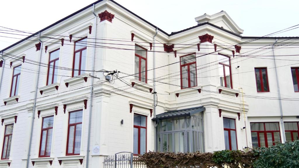 a white building with red windows and power lines at Vila BELVEDERE in Brăila