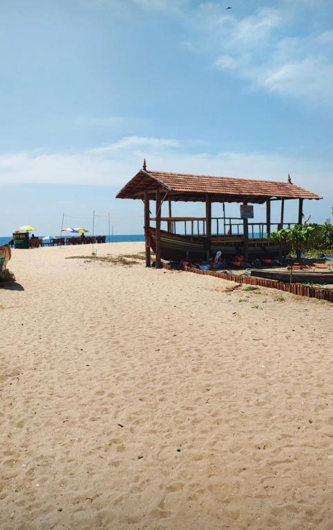 a wooden pavilion on a sandy beach near the ocean at Dolphin beach resort in Varkala