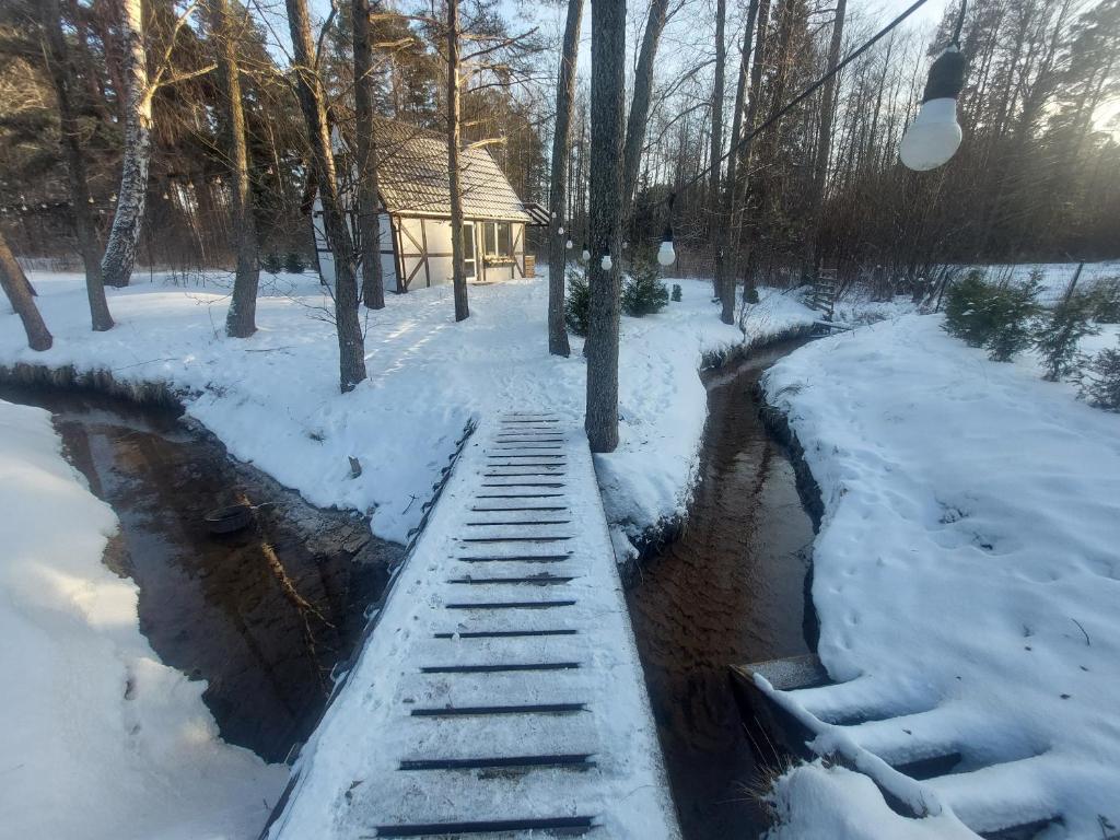 a river with snow on the ground next to a house at small house "Urgas" by the sea with 6 beds in Plieņciems