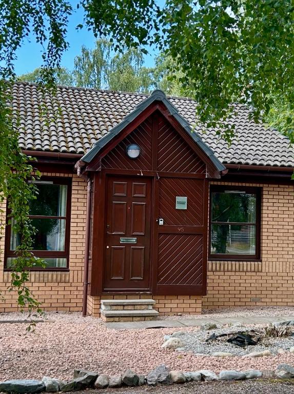 a small house with a brown door and windows at Rendezvous , Aviemore in Aviemore
