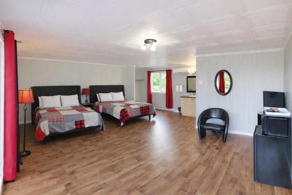 a hotel room with two beds and a television at Motel Au Vieux Frontenac in Thetford Mines