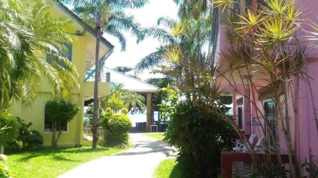 a pink and yellow house with palm trees and a driveway at ไทยพราส in Ban Sam Ngam (2)