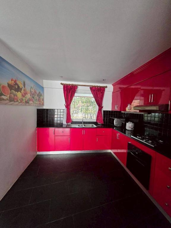 a kitchen with bright red cabinets and a window at Red House 12 in Ban Nong Pru