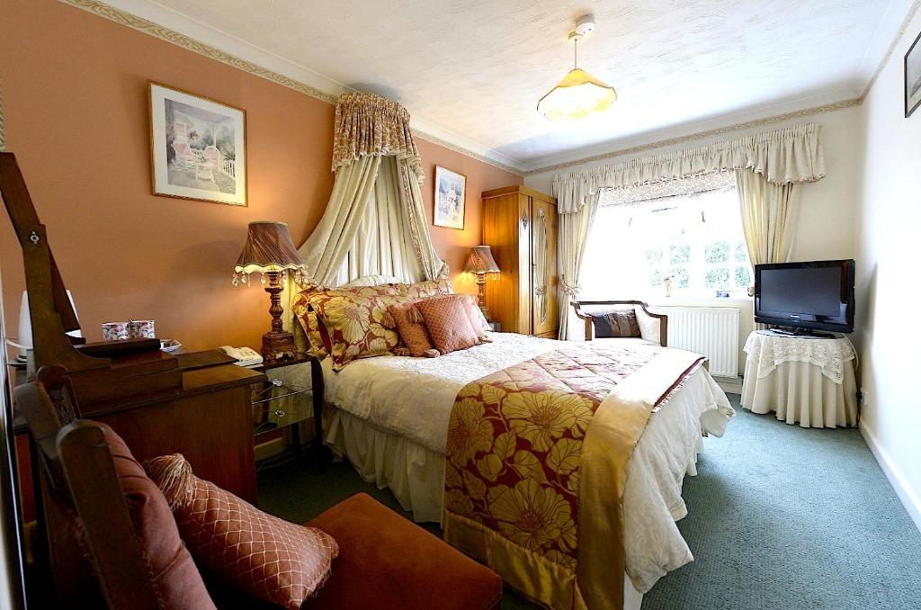 Meryan House Hotel في تونتون: غرفة نوم فيها سرير وتلفزيون