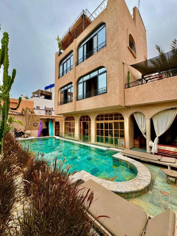 a large building with a swimming pool in front of it at Riad Atlas Surf in Tamraght Ouzdar